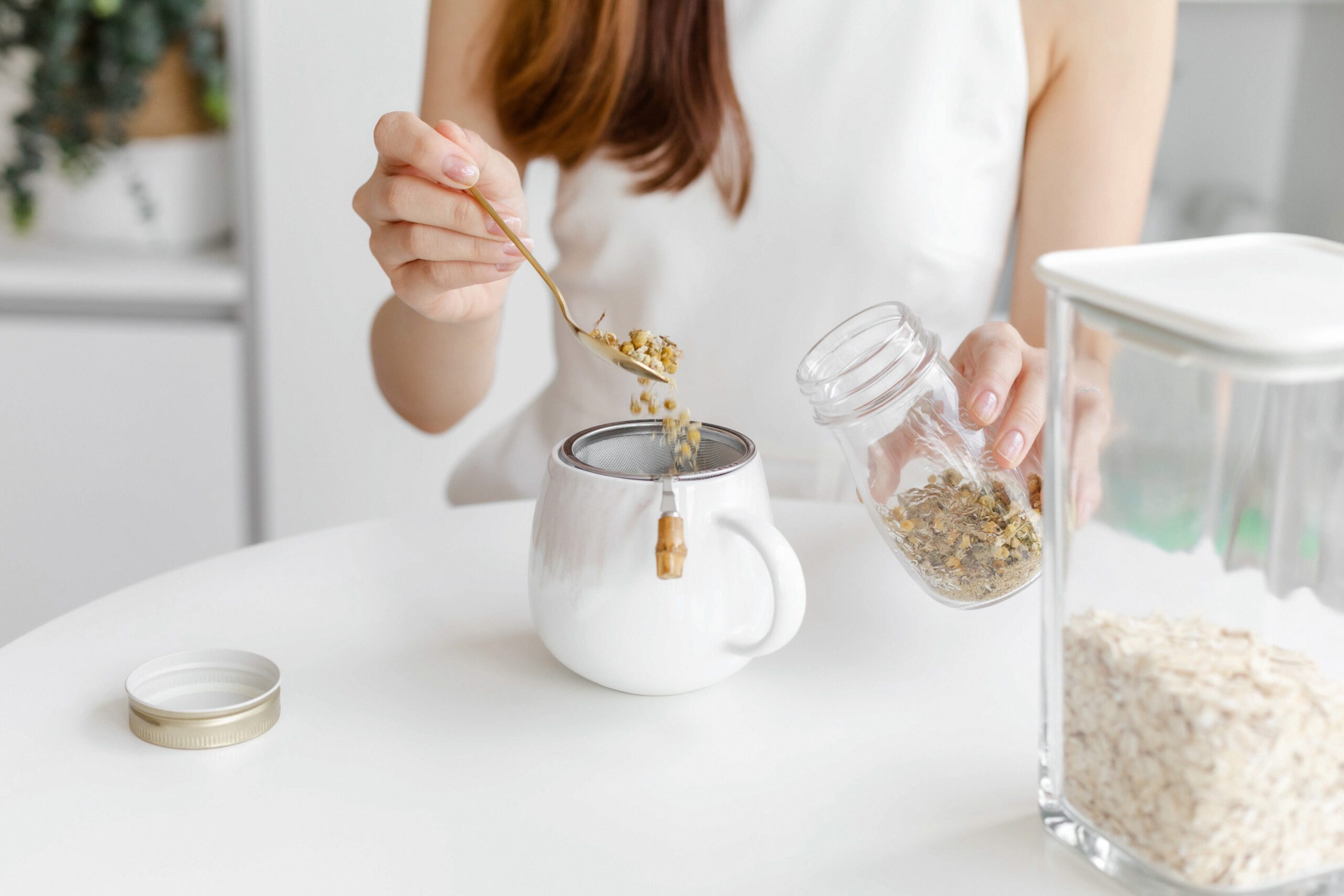 Woman making herbal tea on a white countertop