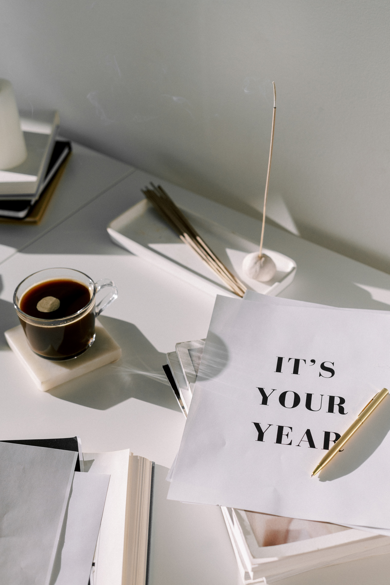 White paper that says "It's your year" on a table with a coffee and a pen